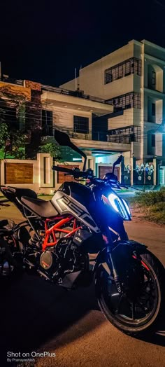 a motorcycle parked in front of a building at night with its headlights on and the lights on