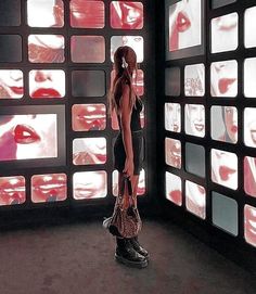 a woman standing in front of multiple televisions with red lipstick on them and her hands behind her head