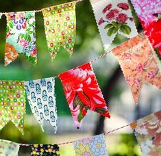 colorful buntings are hanging from a line in the grass with flowers on them