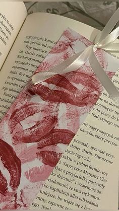 an open book with red lipstick drawn on it's cover and ribbon tied around the edge