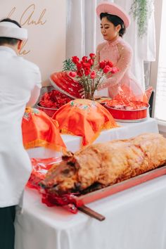 a woman in a pink hat standing next to a table with food and flowers on it