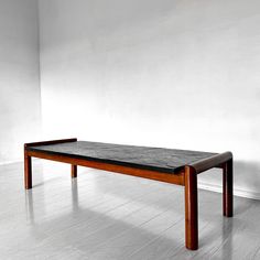 a wooden table sitting on top of a hard wood floor next to a white wall