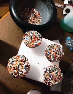 three sprinkled donuts sitting on top of a paper towel next to a cup