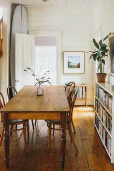 a wooden table sitting in the middle of a living room next to a bookshelf