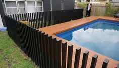 a pool surrounded by a wooden fence in a backyard