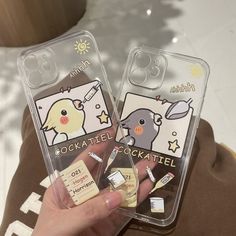 someone holding two cell phones with stickers on them