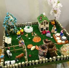 a table topped with fake grass covered in miniature farm animals and people on top of it