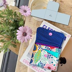 a woman's legs with three small wallets on top of them next to flowers