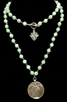 The St. Michael Victory Medallion in Adventurine is 35" long and features the St. Michael Victory Angel Medallion. The 8mm Adventurine gemstones are hand-linked with prayerful intention for the wearer. It is absolutely beautiful all by itself or layered with our other designs. This necklace is long enough to be worn doubled quite comfortably (as shown in first picture). A silver Fleur de Lis accents the clasp to be worn in the front when you wear it doubled or as a lovely enhancement when worn o Adventurine Necklace, Trinity Necklace, Heart Cross Necklace, Gold Bracelets Stacked, Wearing Jewelry, Healing Gemstones, Pearl Necklace Designs, Gold Diamond Necklace, Cluster Necklace