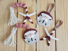 three ornaments made to look like santa claus and other decorations on a wooden table with white tassels