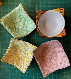 four square dishes sitting on top of a green cutting board next to a white bowl