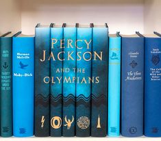 a row of blue books sitting on top of a white book shelf next to each other