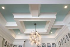 a chandelier hanging from the ceiling in a room with blue walls and white trim