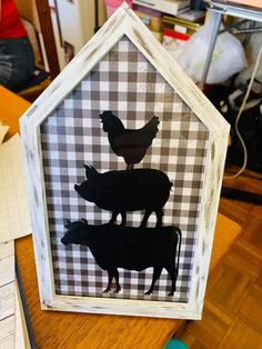 the silhouettes of chickens and pigs are on display in a frame that is sitting on a table