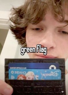 a boy holding up a credit card with the words green flag in front of him