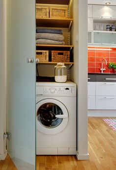 a washer and dryer in a room with wooden floors, white walls and cabinets