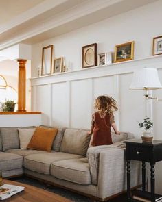 a woman standing on top of a couch in a living room