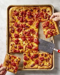 someone cutting into a square pizza on top of a pan