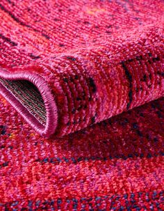 a red rug with an intricate design on the bottom and side is folded in half