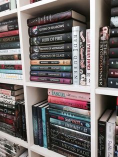 a book shelf filled with lots of books on top of white shelving unit shelves