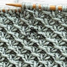 the crochet stitch is being worked on with two knitting needles in front of it