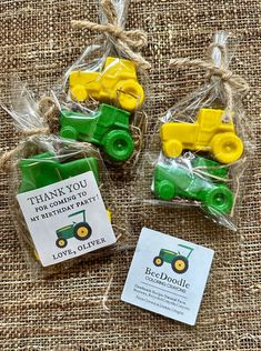 three small green and yellow toy trucks in plastic bags on a burlap background