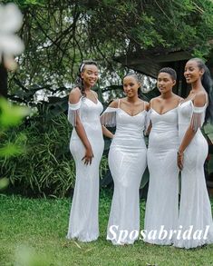 three beautiful women in white dresses posing for the camera with their arms around each other