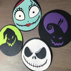 four halloween coasters with faces on them sitting on top of a wooden table next to each other