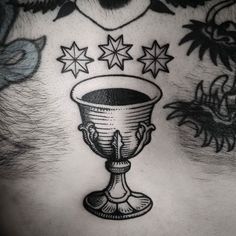 a man's chest with tattoos on it and stars above the cup in the center