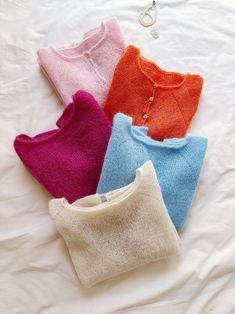 four sweaters laid out on a white sheet