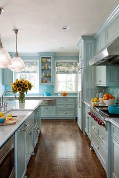 a kitchen filled with lots of blue cabinets and counter top space next to a stove top oven