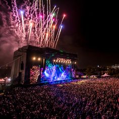 a large crowd is watching fireworks go off in the night sky at an outdoor concert