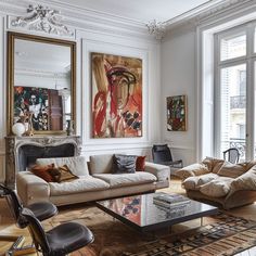 a living room filled with lots of furniture and paintings on the wall above it's windows