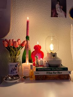 a table topped with books and flowers next to a lit candle on top of it