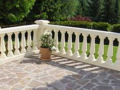 a potted plant sitting on the side of a white balcony with stone flooring