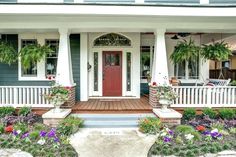 the front porch of a house with flowers and potted plants on either side of it