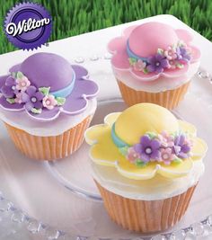 three decorated cupcakes sitting on top of a glass plate