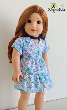 the doll is wearing a blue dress with white flowers on it's chest and brown hair