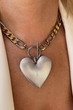 An oversized silver heart pendant hangs from a bold statement figaro link chain with a toggle clasp closure! Chunky Chain Heart Metal Necklace, Heart-shaped Metal Toggle Necklace With Adjustable Chain, Metal Heart Pendant Necklace With Toggle Clasp, Heart Pendant Necklace With Toggle Clasp, Metal Heart Toggle Necklace With Heart Charm, Metal Toggle Necklace With Heart Charm, Thick Chain Necklace, Figaro Chain Necklace, Toggle Necklace