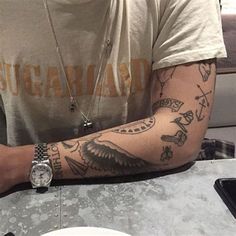 a man with tattoos sitting at a table