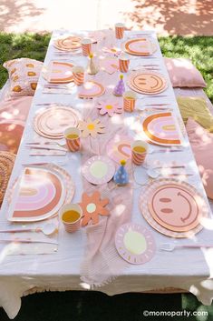 a table set up with plates, cups and napkins for an outdoor birthday party