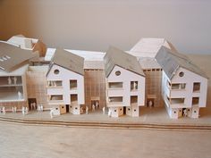 a group of model houses sitting on top of a wooden table next to each other