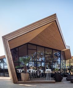 a wooden structure with tables and chairs in front of it on top of a deck