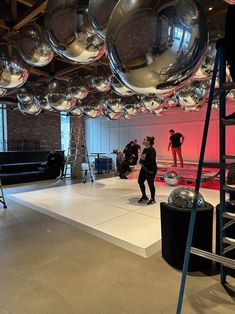 some people are doing something in a room with shiny balls on the ceiling and ladders