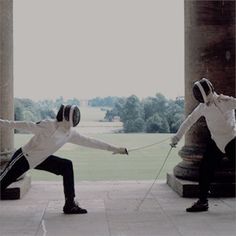 two men in white shirts and black pants are pulling each other by strings with their hands