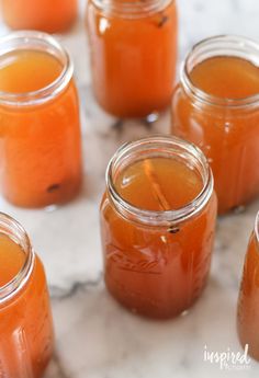 several jars filled with liquid sitting on top of a marble counter next to each other