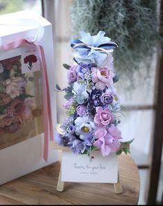 a bouquet of flowers sitting on top of a wooden table next to a card box