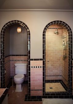 the bathroom is decorated in pink and black tile, along with two separate shower stalls