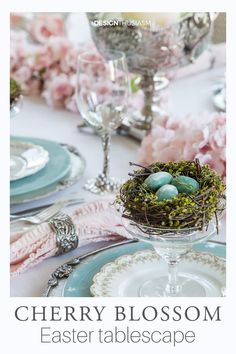 the table is set with plates, silverware and an arrangement of eggs in a nest