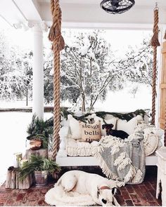 a dog laying on a porch swing in the snow